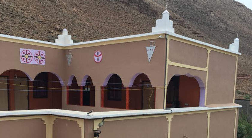 Façade de l'Auberge Pied du Siroua à Tagmoute : arcades, motifs berbères peints et montagne en arrière-plan