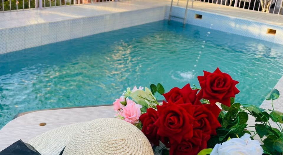 The swimming pool at Auberge Pied du Siroua in Tagmoute, with a bouquet of roses and a straw hat at the water's edge