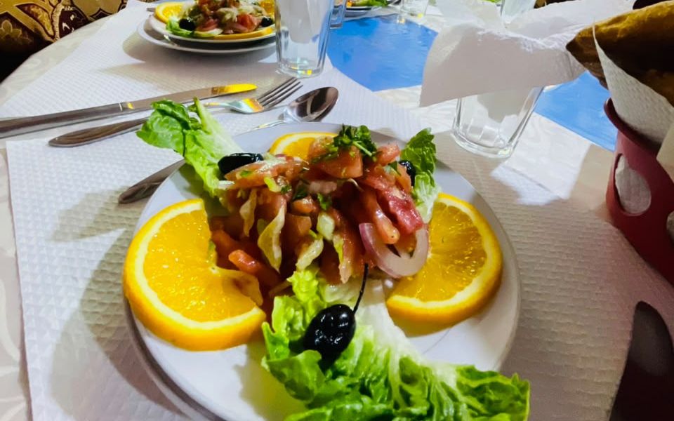 Salade marocaine aux tranches d'orange servie dans la salle du restaurant de l'auberge, à Tagmoute