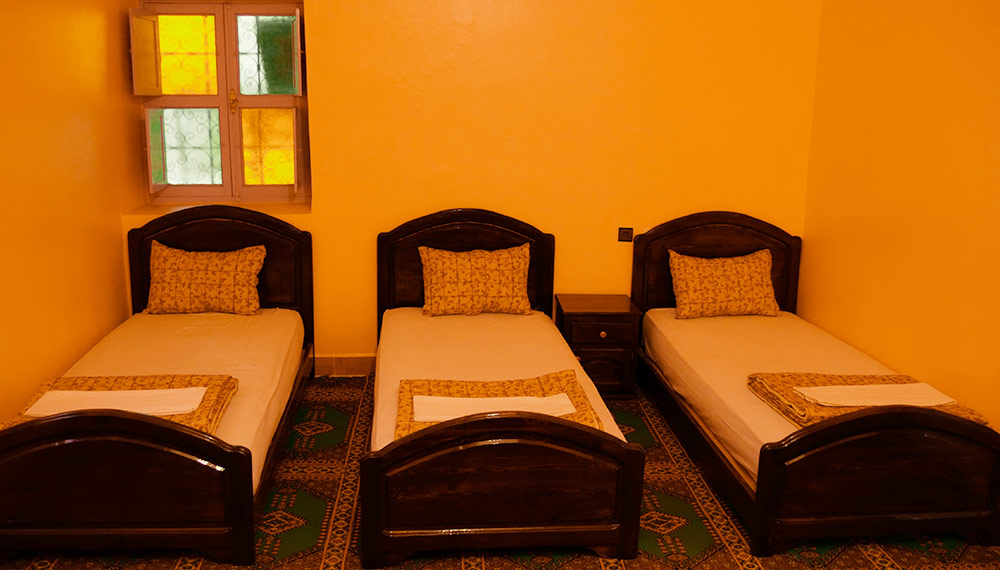 Family room with yellow walls and three single beds in a row