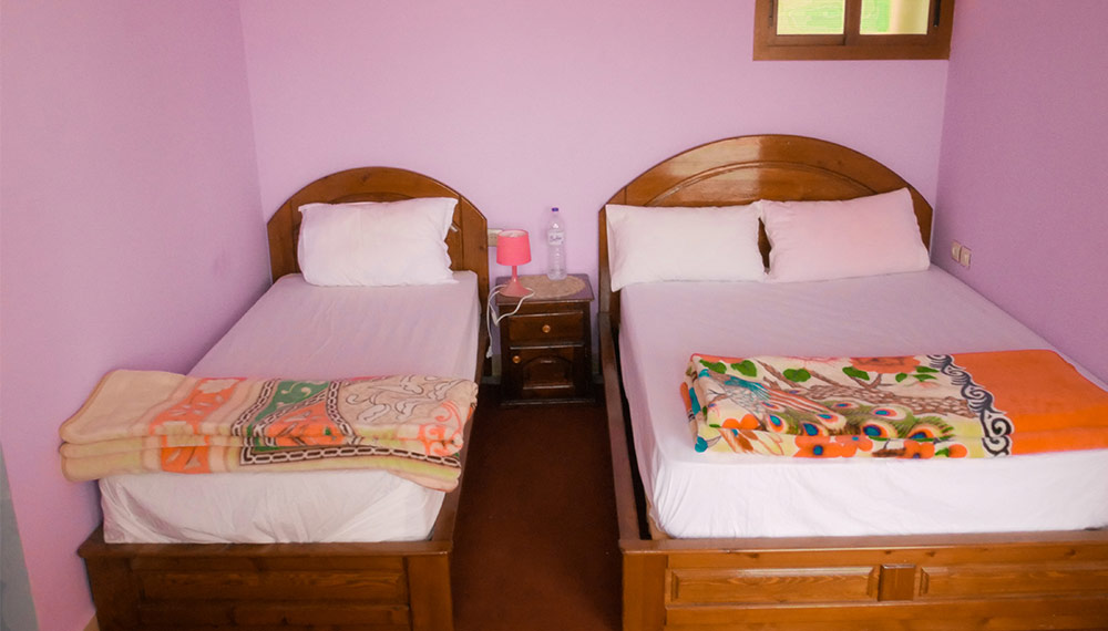 Two single beds with colourful blankets and a bedside lamp