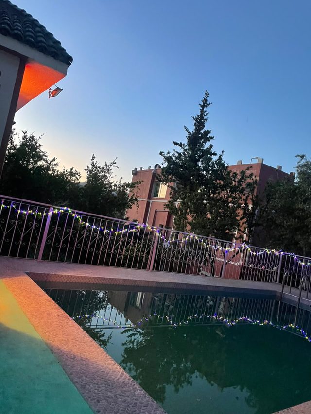 La piscine de l'auberge au crépuscule, ses guirlandes lumineuses reflétées dans l'eau