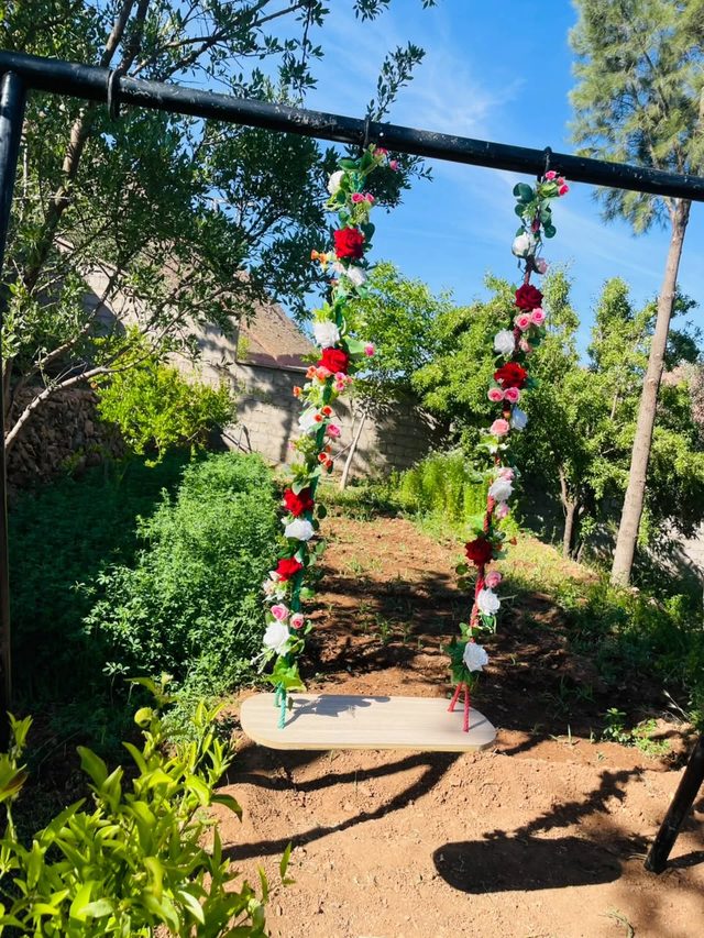 Balançoire ornée de roses dans le jardin de l'Auberge Pied du Siroua, à Tagmoute