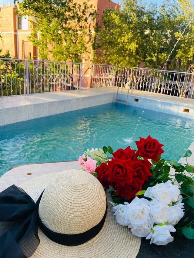 Bouquet de roses rouges, roses et blanches et chapeau de paille au bord de la piscine de l'auberge