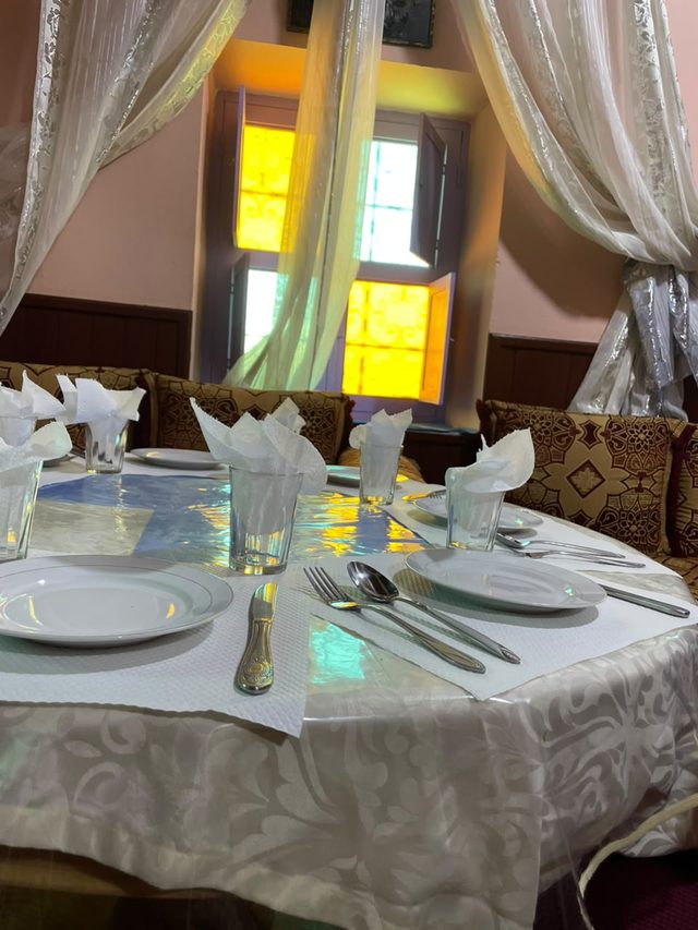 Table ronde dressée dans la salle du restaurant, devant la fenêtre aux vitraux colorés
